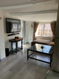 a living room with a couch and a table at woodpecker cottage at frog trotters cottages in Hartpury