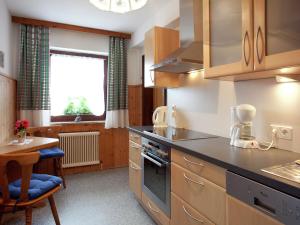 a kitchen with a stove and a table and a window at Sunny holiday flat with balcony in Wagrain
