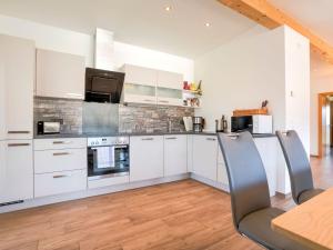 cocina con armarios blancos, mesa y sillas en Apartment directly on the Weissensee in Carinthia, en Weissensee