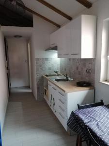 cocina con armarios blancos, fregadero y mesa en Apartment Camerin en Koper