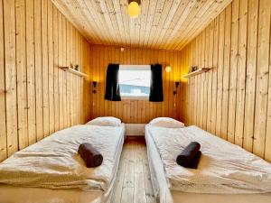 two beds in a room with wooden walls and a window at Inuk Hostels in Nuuk