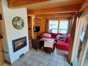 ein Wohnzimmer mit einem roten Sofa und einem Kamin in der Unterkunft Chalet in St Georgen ob Murau with hot tub in Sankt Georgen ob Murau