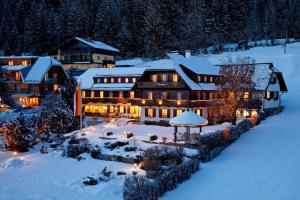 a large house in the snow with lights at Seehotel Enzian in Weissensee