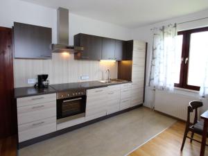 a kitchen with white cabinets and a stove top oven at Apartment in Koettmannsdorf near bathing lakes in Köttmannsdorf