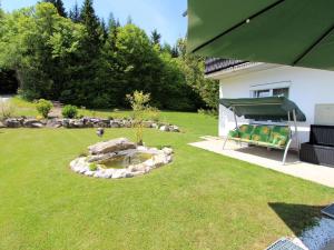 einen Garten mit einem Teich und einem grünen Sonnenschirm in der Unterkunft Apartment in Koettmannsdorf near bathing lakes in Köttmannsdorf