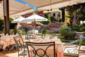 a restaurant with white tables and chairs and umbrellas at Grupotel Playa Club in Son Xoriguer