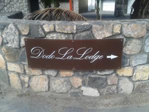 un cartello per Aldeorias la lobby su un muro di pietra di Dodola Lodge a Pereybere