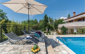 a patio with chairs and an umbrella next to a swimming pool at Amazing Home In Labin With Jacuzzi in Labin