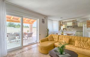 a living room with a yellow couch and a kitchen at Cozy Home In Stinjan With Outdoor Swimming Pool in Štinjan