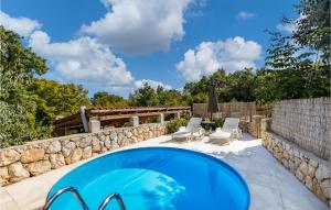 a pool with two chairs and a stone wall at Gorgeous Home In Krk With House A Panoramic View in Risika