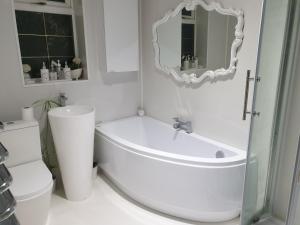 a white bathroom with a tub and a toilet at Tropical Garden Oasis Rooms in Birmingham +36 photos