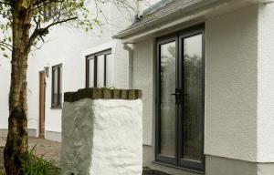 a white house with a door and a tree at Mountain View Apartment - short drive to beaches in Bryngwran