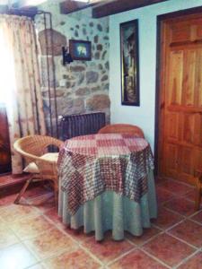 Habitación con mesa, sillas y pared de piedra. en La Casa del Valle, en Ailanes