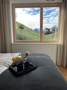 a tray with two glasses of orange juice on a bed with a window at Nesensohn Ferienwohnungen in Batschuns