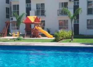 une piscine avec toboggan en face d'un bâtiment dans l'établissement Turqueza Friends., à Cancún