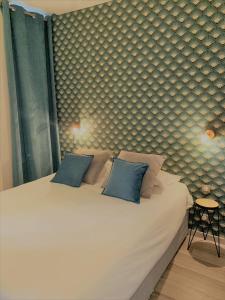 um quarto com uma grande cama branca com almofadas azuis em Hôtel de Bretagne Dol centre ville em Dol-de-Bretagne