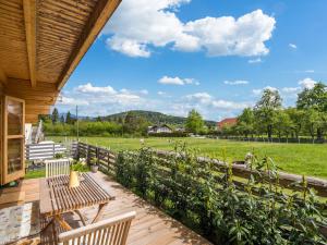 a deck with a table and chairs and a field at Chalet in Finkenstein Carinthia on Lake Faak in Ledenitzen