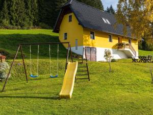 a playground in front of a yellow house with a slide at Holiday home in Eberstein near Woerthersee in Eberstein
