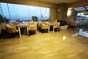a restaurant with tables and chairs and large windows at Inciler Hotel in Altınoluk