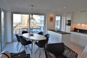 een keuken en een woonkamer met een tafel en stoelen bij Lichtrijk 2-slaapkamerappartement met zeezicht en gratis parking in Oostende