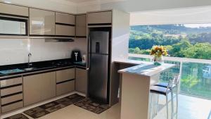 a kitchen with a refrigerator and a counter with a window at Thermas Palace in Piratuba