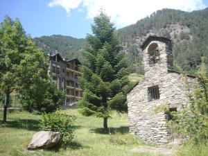 an old stone building in a field next to a building at Aparthotel Sant Andreu in Arinsal