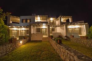 a house with lights on the side of it at night at To Pithari in Skiros