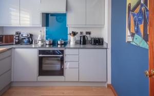 a kitchen with white cabinets and a stove top oven at Paradise Place in Perth