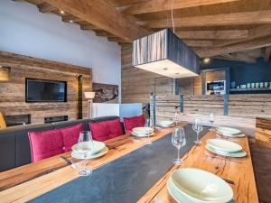 ピーゼンドルフにあるLuxurious holiday home in Piesendorf with saunaのダイニングルーム(長い木製テーブル、赤い椅子付)