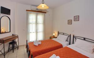 a bedroom with two beds and a desk and a mirror at To Pithari in Skiros