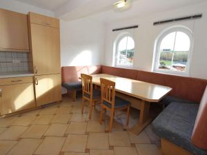 eine Küche mit einem Holztisch und Stühlen sowie 2 Fenstern in der Unterkunft Luxurious Mansion in Goldegg near Skiing Area in Goldegg