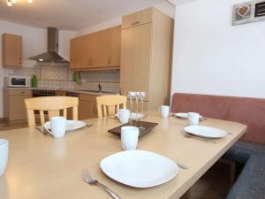 - une table en bois avec des assiettes et des ustensiles blancs dans l'établissement Luxurious Mansion in Goldegg near Skiing Area, à Goldegg