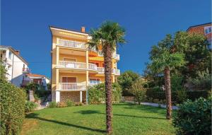 a yellow building with palm trees in front of it at Cozy Apartment In Selce With Kitchen in Selce