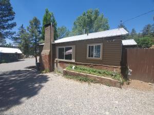 a small brown house with a window on a street at Enchanted Hideaway Cabins and Cottages in Ruidoso