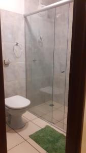 La salle de bains est pourvue de toilettes et d'une douche en verre. dans l'établissement Pousada Fênix, à Pirenópolis