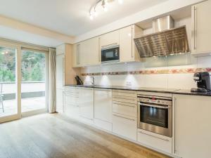 a kitchen with white cabinets and a large window at Modern Apartment in Saalbach Hinterglemm near Ski Aea in Saalbach-Hinterglemm