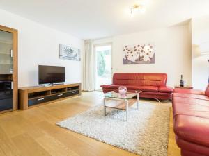 a living room with a red couch and a tv at Modern Apartment in Saalbach Hinterglemm near Ski Aea in Saalbach-Hinterglemm