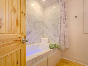a white bathroom with a tub and a shower at Downtown Fairhope Cottage in Fairhope