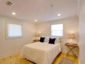 a bedroom with a large bed with two windows at Downtown Fairhope Cottage in Fairhope