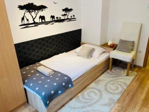 a small bedroom with a bed and a chair at Origo Apartman in Eger