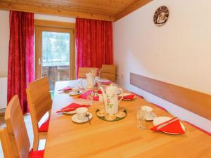 a dining room with a wooden table with red curtains at Cozy apartment in Wald K nigsleiten in Wald im Pinzgau