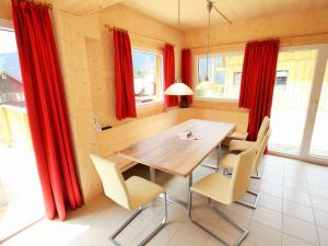 Nice chalet in Hohentauern Styria with sauna في هوهنتاورن: غرفة طعام مع ستائر حمراء وطاولة وكراسي خشبية