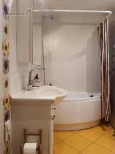 a white bathroom with a sink and a bath tub at Penthouse apartment in Mažeikiai