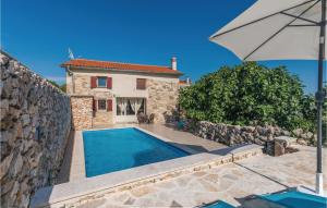 a villa with a swimming pool in front of a house at Beautiful Home In Krk With 2 Bedrooms, Wifi And Outdoor Swimming Pool in Garica
