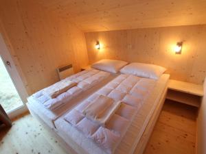 um quarto com uma cama grande e almofadas brancas em Wooden chalet in Hohentauern Styria with sauna em Hohentauern