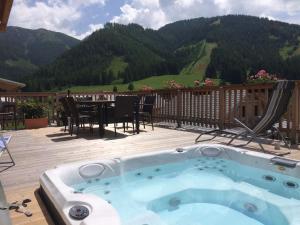 霍亨陶恩的住宿－Wooden chalet in Hohentauern Styria with sauna，甲板上的热水浴池配有桌椅