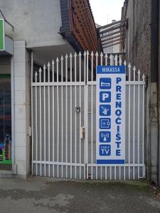 um portão branco com um sinal em frente a um edifício em Mikasa em Niš