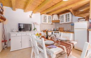 uma cozinha com mesa e cadeiras e uma cozinha com armários brancos em Amazing Home In Lubenice With Wifi em Lubenice