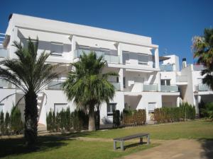 un edificio blanco con palmeras delante en Apartamentos Fercamar Denia, en Denia