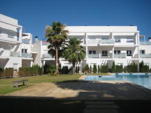 un gran edificio blanco con piscina y palmeras en Apartamentos Fercamar Denia, en Denia